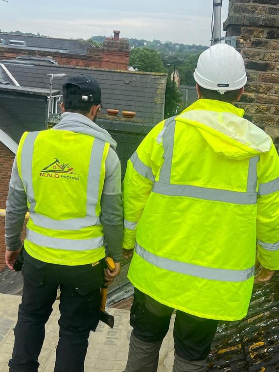 Two M.N.O roofers in branded hi-vis jackets on a London roof
